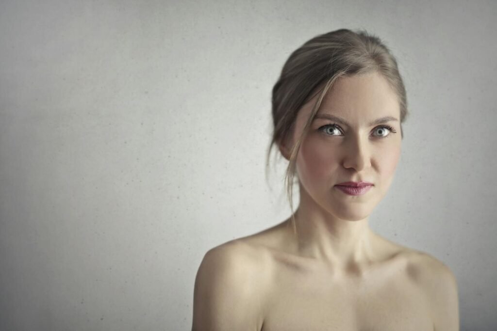 Stunning close-up portrait of a young woman with captivating eyes and a serene expression against a gray background.