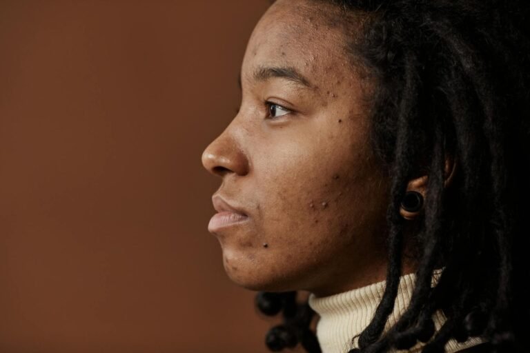 Profile portrait of a young woman with natural hair and visible skin texture.