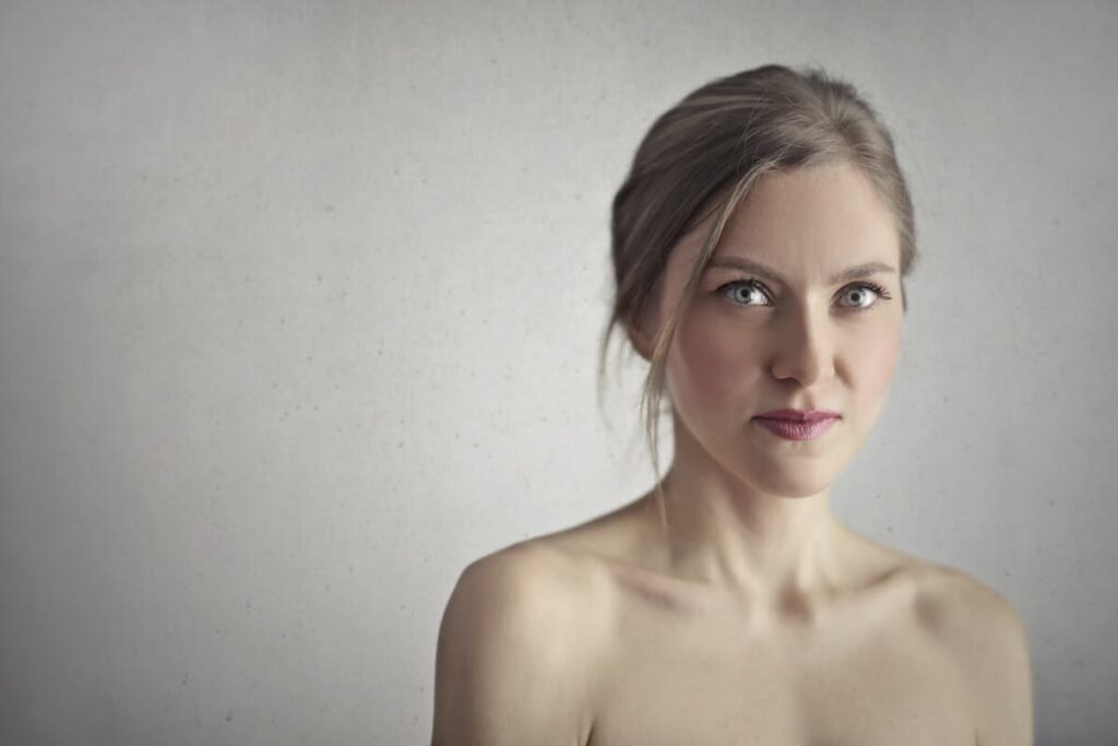 Stunning close-up portrait of a young woman with captivating eyes and a serene expression against a gray background.