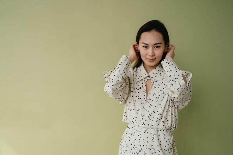 Charming woman in a stylish patterned dress posing against a soft green backdrop.