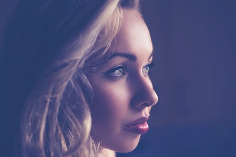 Captivating side profile of a young woman with blonde hair, expressive eyes, and soft lighting.